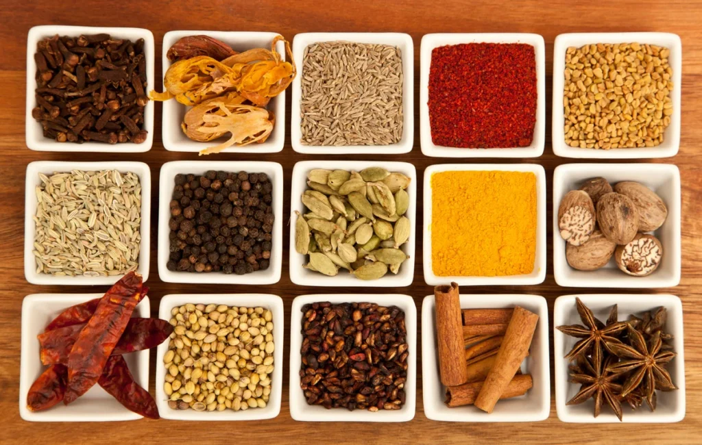 Indian spices including cardamom, turmeric, chilli, cloves, cinnamon and star anise arranged in small bowls