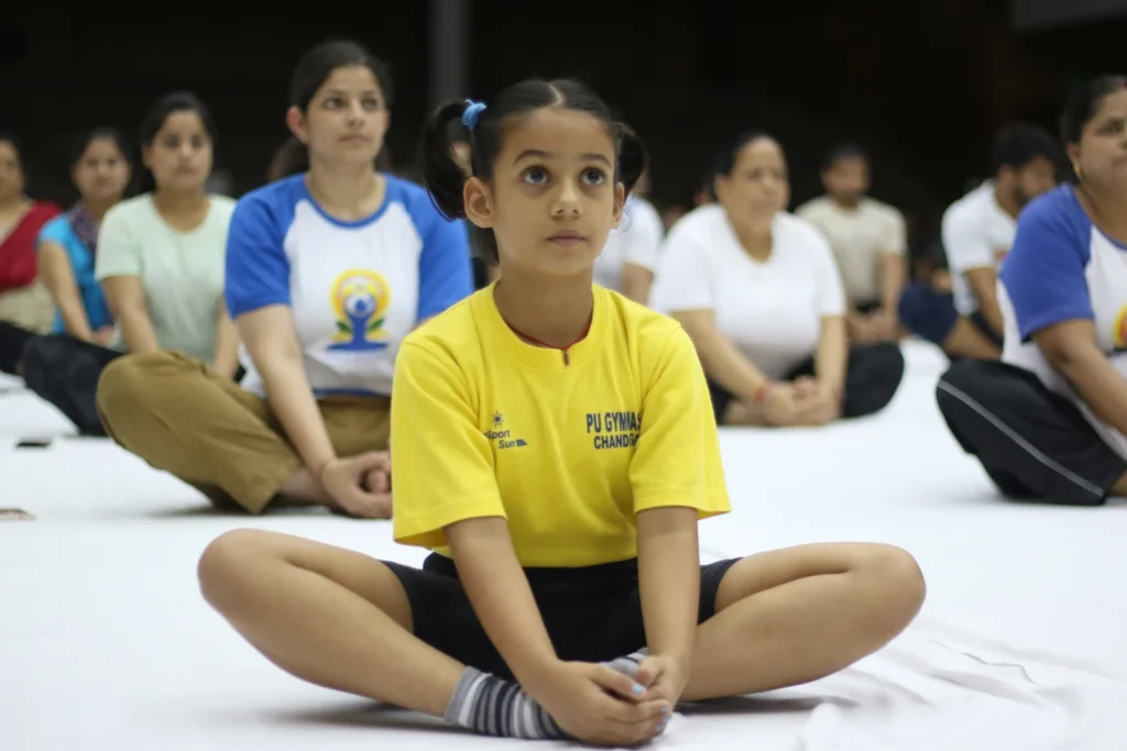 Students and adults practising a seated yoga posture at Panjab University in Chandigarh